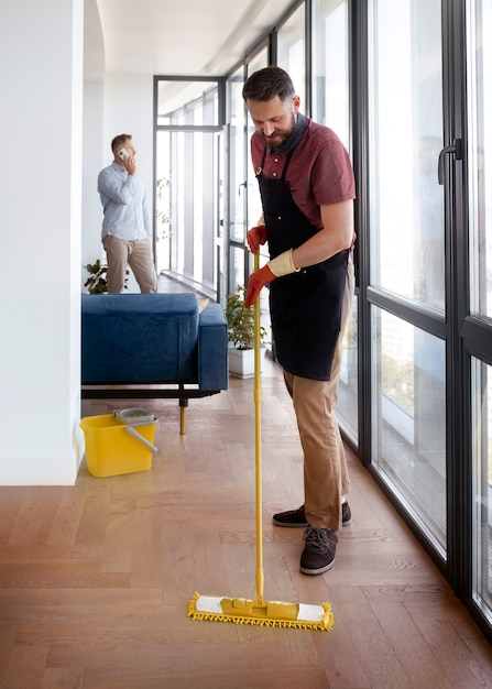 Professional cleaner mopping office floor near glass windows