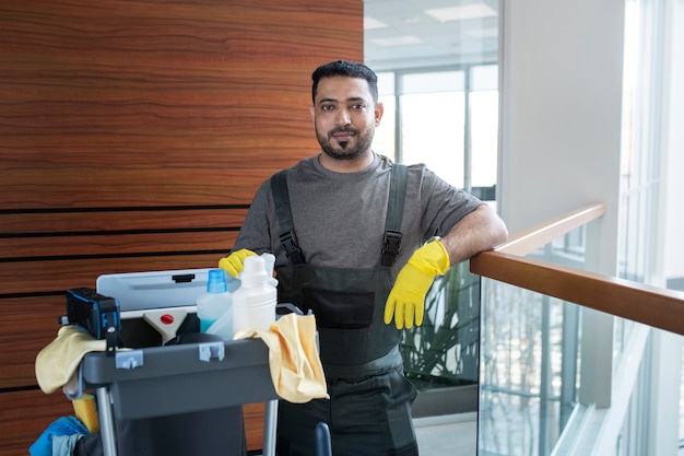 Professional commercial cleaner with cleaning supplies in office building